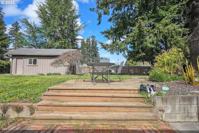 wooden deck with fence, outdoor dining space, an outbuilding, and a yard