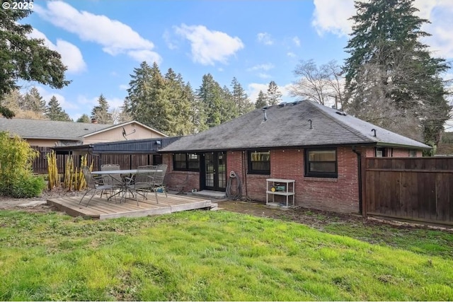 rear view of property with fence, a deck, a lawn, and french doors