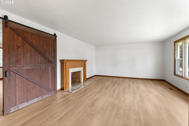 unfurnished living room featuring a barn door and light wood-type flooring