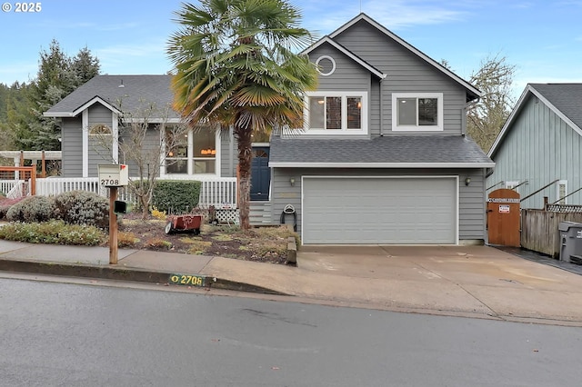 view of front facade featuring an attached garage, a shingled roof, fence, and concrete driveway