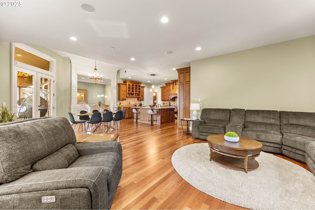 living area with recessed lighting, light wood finished floors, and a notable chandelier