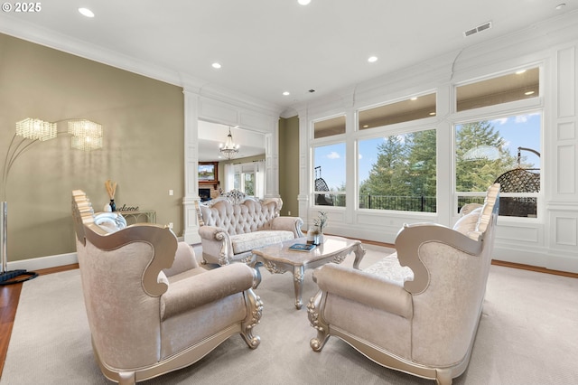 living room with crown molding, a fireplace, a chandelier, and light wood-type flooring