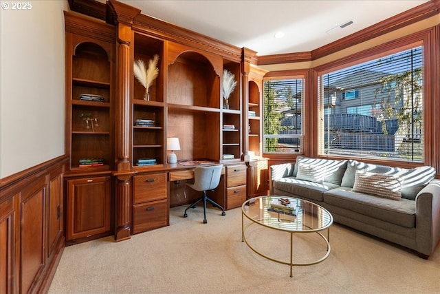 office featuring visible vents, crown molding, wainscoting, built in study area, and light colored carpet