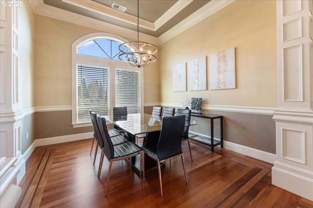 dining area with a raised ceiling, crown molding, a notable chandelier, and dark hardwood / wood-style flooring