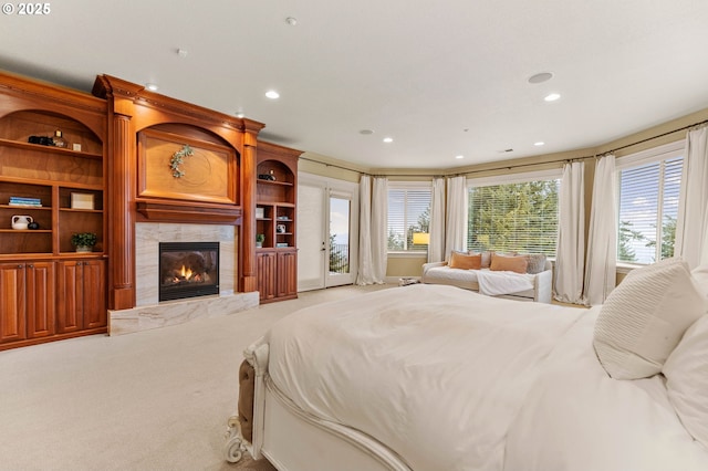 bedroom with multiple windows, access to outside, light colored carpet, and a fireplace