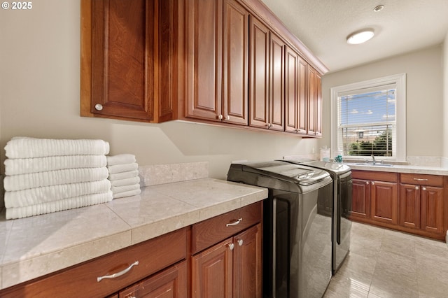 laundry area with cabinets, washing machine and clothes dryer, sink, and a textured ceiling