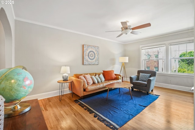 living room with crown molding, wood finished floors, baseboards, and a ceiling fan