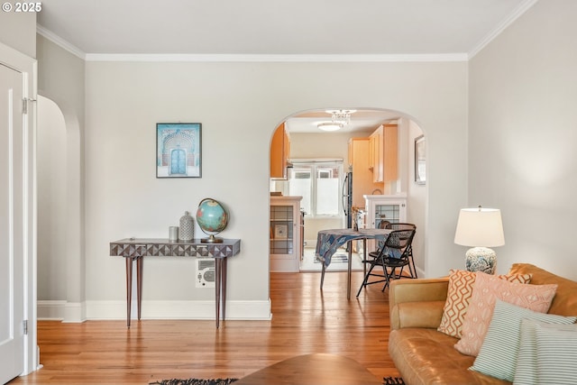 living area featuring arched walkways, light wood-type flooring, ornamental molding, and baseboards
