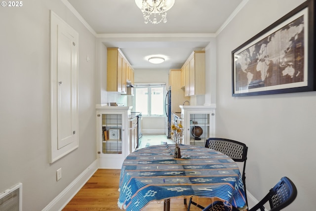 dining space with light wood-style flooring, a chandelier, baseboards, and crown molding
