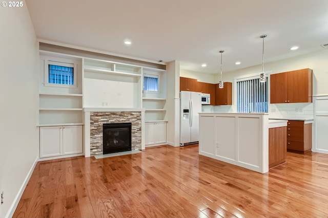 8006 SE Sporri Ln, Milwaukie, OR 97267 - kitchen with white appliances, brown cabinetry, light countertops, light wood-style floors, and a center island