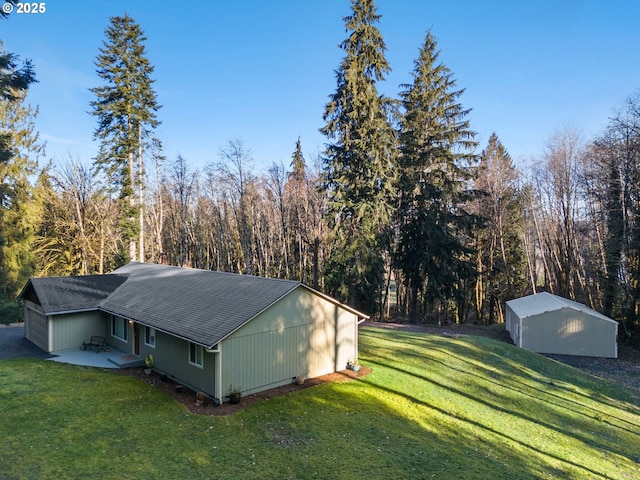 view of property exterior featuring a patio, an outdoor structure, a lawn, and a view of trees