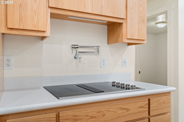 kitchen with light brown cabinetry, black electric stovetop, and light countertops
