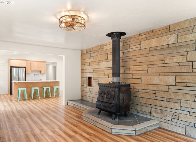 unfurnished living room with a wood stove and light wood-style flooring