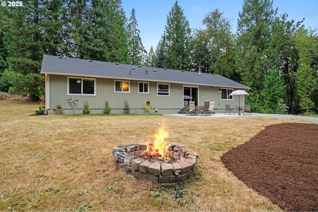 rear view of house with an outdoor fire pit, a lawn, and a patio area