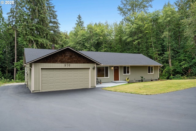 ranch-style house with an attached garage, driveway, roof with shingles, and a front yard