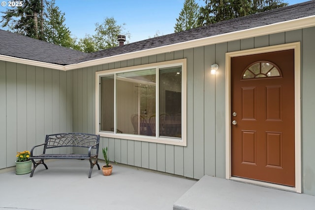 entrance to property with a patio area and roof with shingles