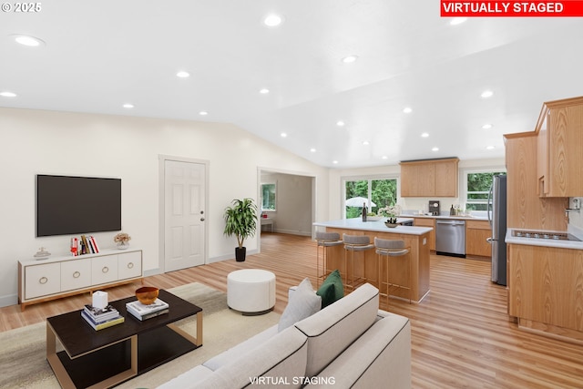 kitchen with a kitchen bar, a center island, light wood-type flooring, light countertops, and stainless steel appliances