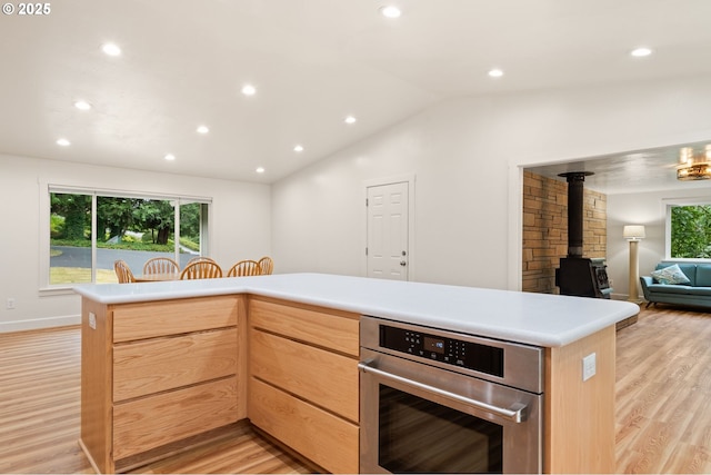 kitchen featuring a wood stove, oven, light wood-style flooring, and light brown cabinetry