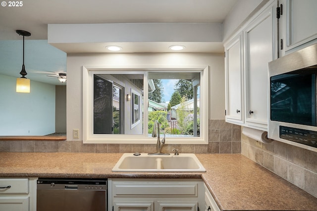kitchen featuring a sink, stainless steel appliances, white cabinetry, backsplash, and pendant lighting