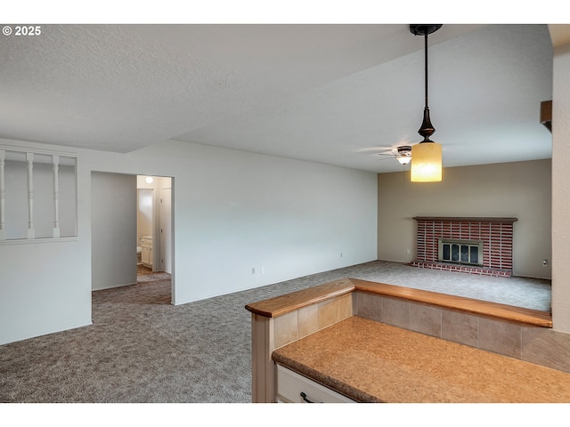 kitchen featuring a brick fireplace, carpet, and ceiling fan