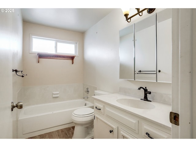 bathroom featuring toilet, wood finished floors, a bath, and vanity