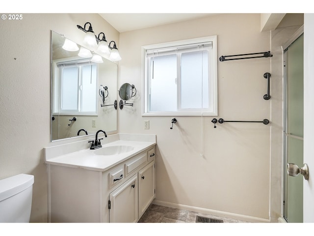bathroom with visible vents, a shower with shower door, vanity, baseboards, and toilet