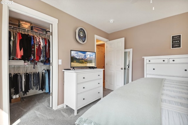 bedroom featuring a spacious closet, baseboards, a closet, and light colored carpet