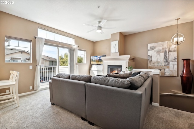 living area featuring carpet, ceiling fan with notable chandelier, a healthy amount of sunlight, and a fireplace