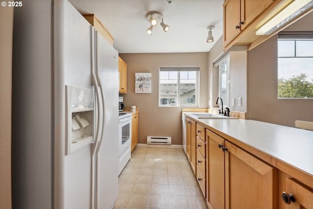 kitchen with a sink, white appliances, light countertops, a wealth of natural light, and a baseboard radiator