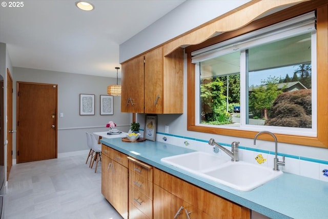 15 SW 95th Ave, Portland, OR 97225 - kitchen with a sink, light countertops, hanging light fixtures, brown cabinetry, and baseboards