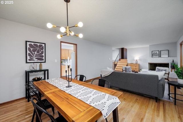 15 SW 95th Ave, Portland, OR 97225 - dining area featuring stairway, a chandelier, light wood-style flooring, baseboards, and a fireplace