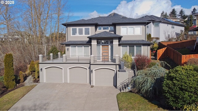 prairie-style house with stucco siding, fence, a balcony, a garage, and driveway