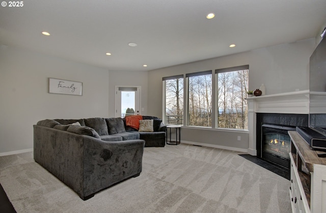 living room featuring recessed lighting, a fireplace with flush hearth, baseboards, and light colored carpet