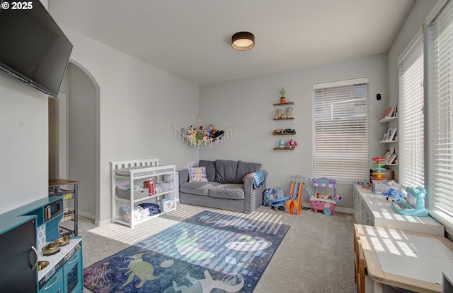 game room with carpet, arched walkways, and baseboards