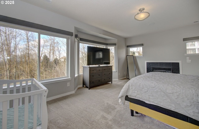 bedroom featuring a tile fireplace, light colored carpet, and baseboards