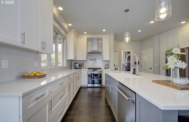 kitchen featuring stainless steel appliances, white cabinetry, a sink, and wall chimney exhaust hood