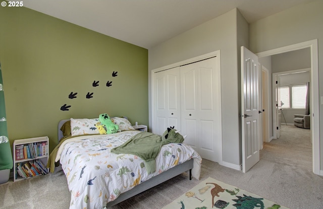 bedroom with a closet, light colored carpet, and baseboards