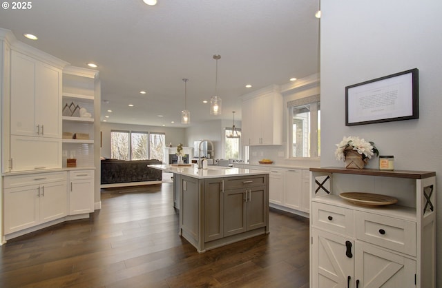 kitchen featuring hanging light fixtures, a kitchen island with sink, white cabinets, and a sink