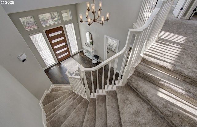 foyer with stairs, a high ceiling, dark carpet, and a chandelier