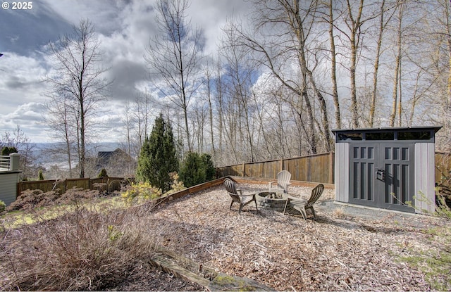 view of yard featuring an outbuilding, a shed, an outdoor fire pit, and a fenced backyard