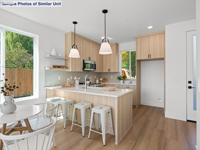 1218 SE Center St Unit 3, Portland, OR 97202 - kitchen with stainless steel microwave, light brown cabinetry, modern cabinets, light wood finished floors, and recessed lighting