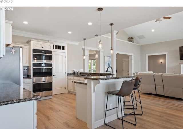 217 Deal Canyon Rd, La Grande, OR 97850 - kitchen with appliances with stainless steel finishes, a kitchen bar, light wood finished floors, ceiling fan, and lofted ceiling
