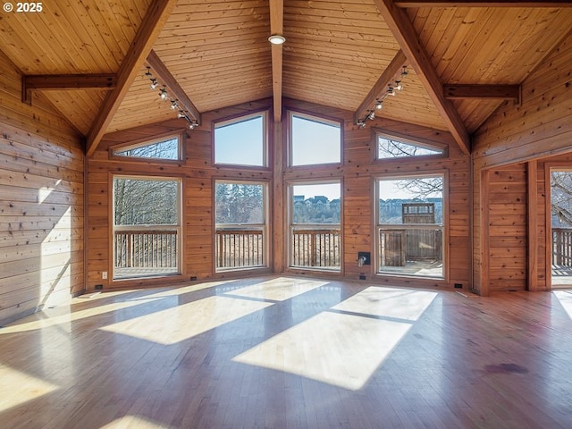 unfurnished living room featuring hardwood / wood-style flooring, wooden walls, and beam ceiling