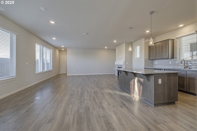 kitchen with a kitchen breakfast bar, a center island, light wood-type flooring, and a sink