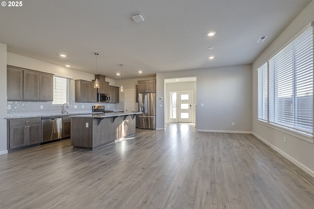 kitchen with tasteful backsplash, a kitchen island, appliances with stainless steel finishes, and a breakfast bar area