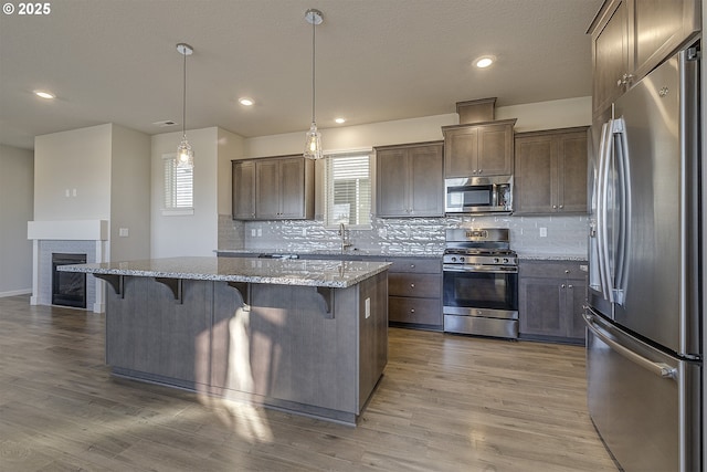 kitchen with a healthy amount of sunlight, stainless steel appliances, a kitchen bar, and wood finished floors