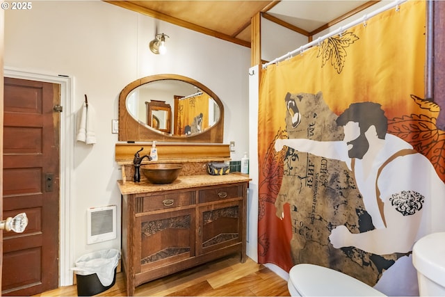 bathroom featuring wood-type flooring, toilet, heating unit, and vanity