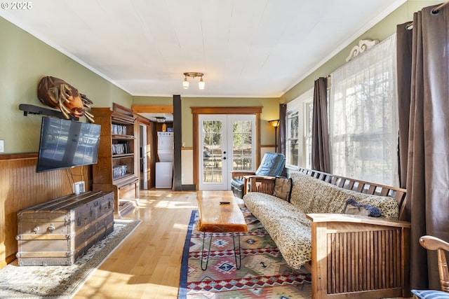 living room with french doors, crown molding, light hardwood / wood-style floors, and wood walls