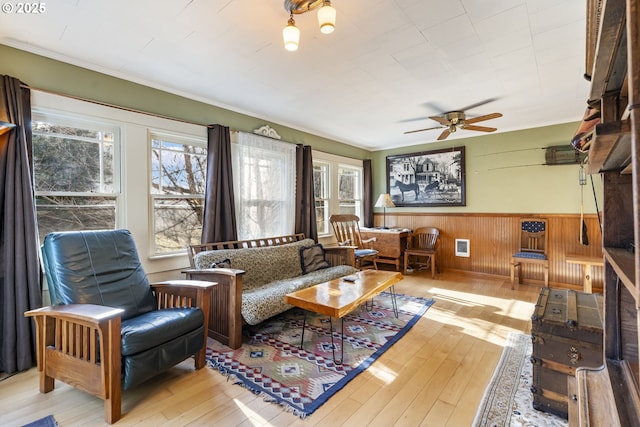 living room with light hardwood / wood-style floors, ceiling fan, and wooden walls