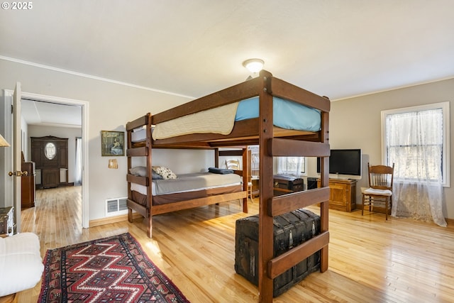 bedroom featuring ornamental molding, multiple windows, and hardwood / wood-style floors